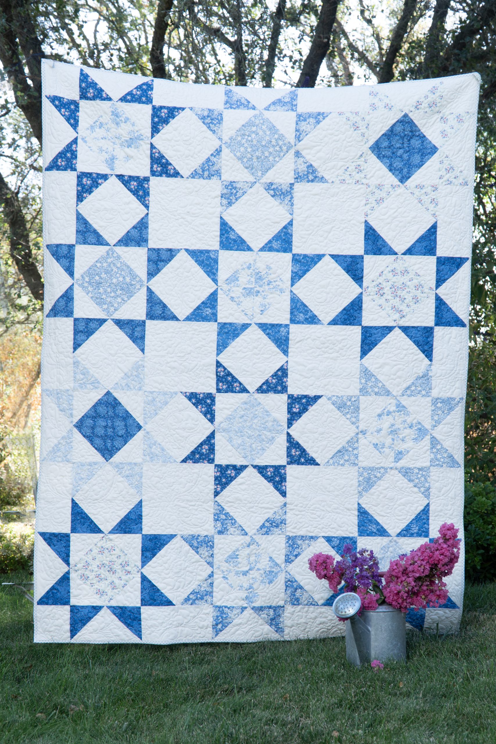 Blue and white star-pattern patchwork quilt draped outdoors
